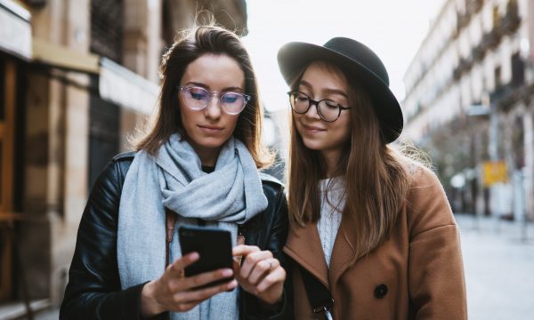 Tourists girls using smartphone plans trip on internet mobile phone. Weekend europe city. Travelers in glasses hold cellphone travels in Barcelona